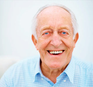 Älterer Mann mit blauen Augen lächelt freundlich und zeigt seine gesunde Zähne.